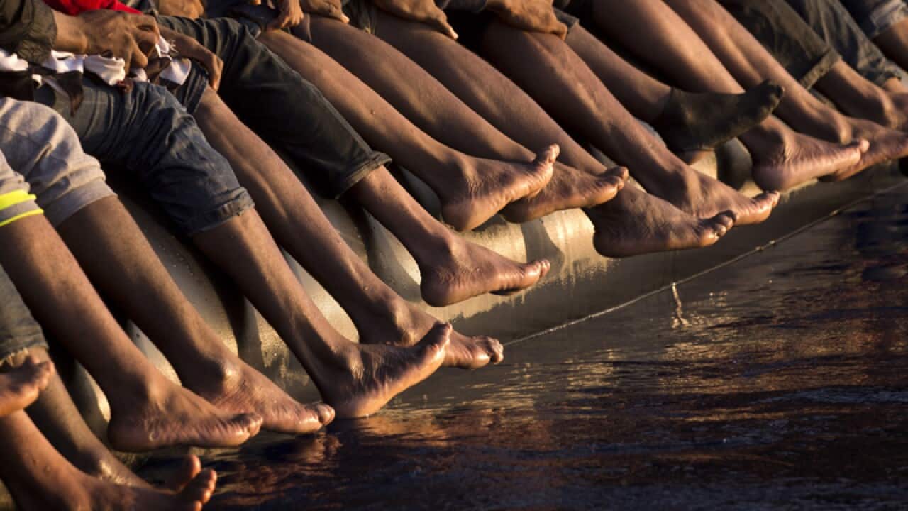 The feet of migrants hang off a dinghy