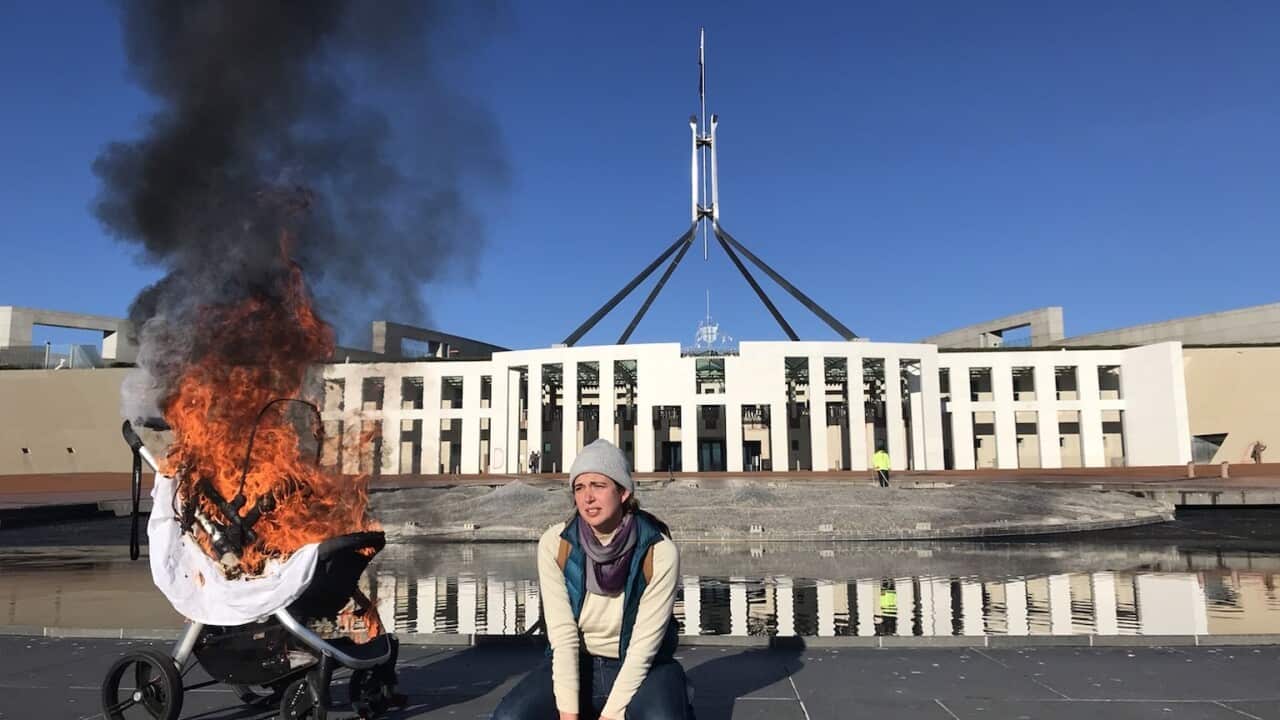 A supplied image shows a woman with a burning pram during an Extinction Rebellion protest outside Parliament House in Canberra, Tuesday, August 10, 2021. (AAP Image/Supplied by Extinction Rebellion) NO ARCHIVING, EDITORIAL USE ONLY