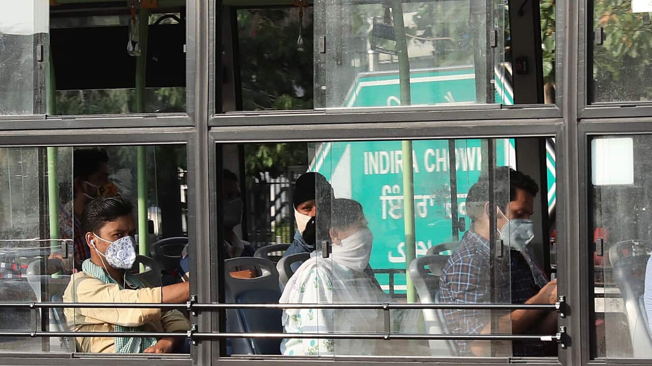 Indian commuters with face masks travel in the Delhi Transport Corporation city bus sitting with social distancing in New Delhi, India, 20 July 2020.