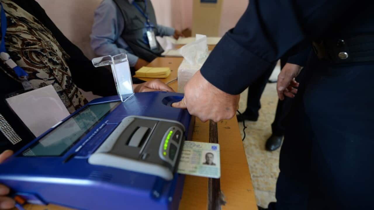 An Iraqi soldier puts his thumb on voter card reading machine