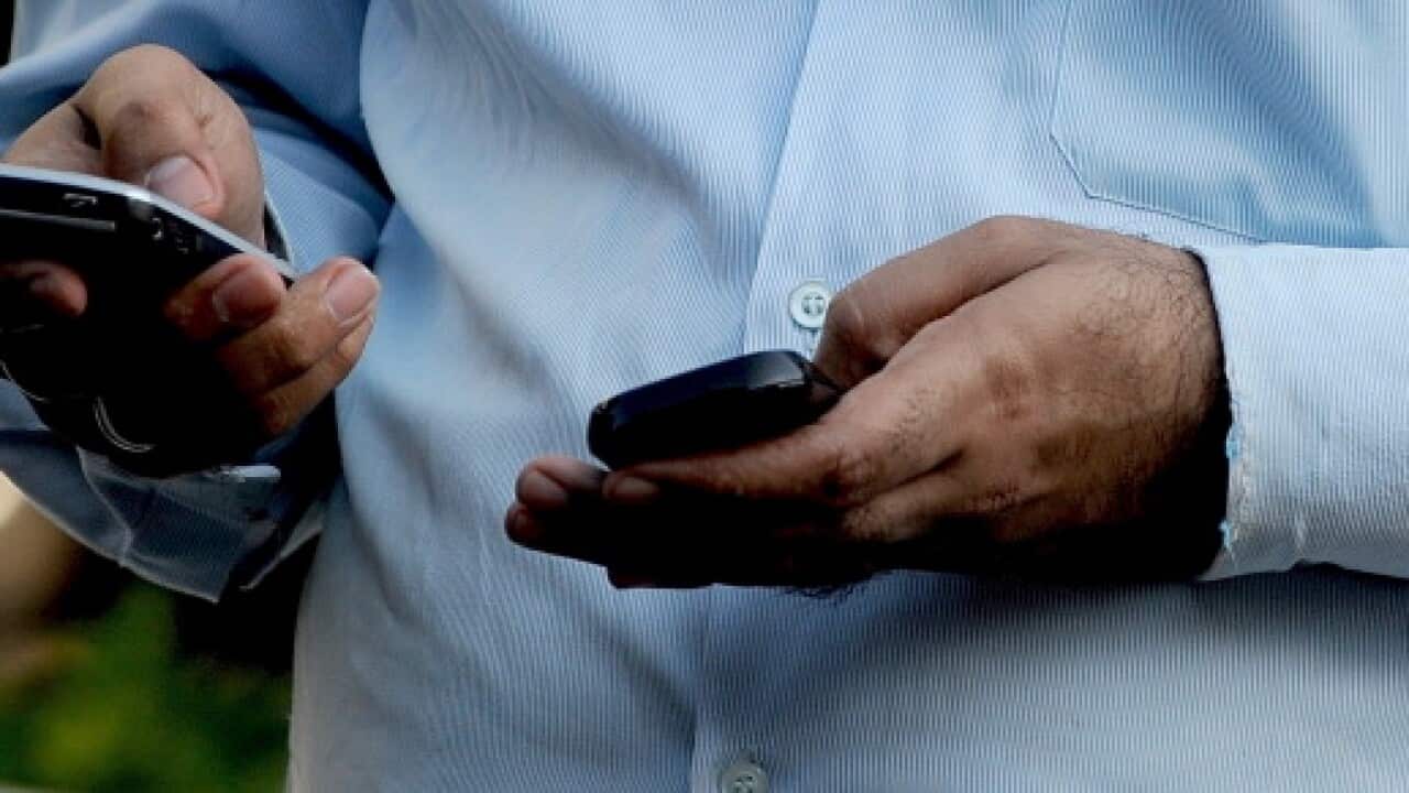 An Indian officegoer checks a text message