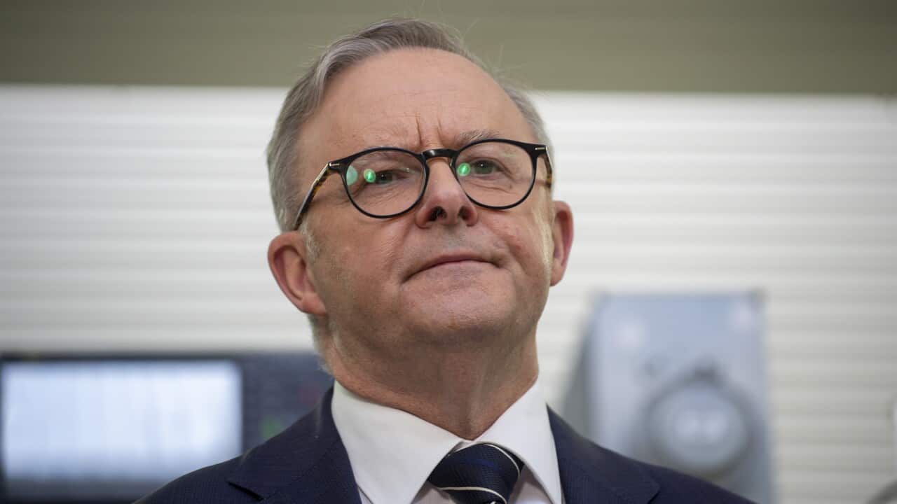 A man in suit and tie wearing glasses looks on
