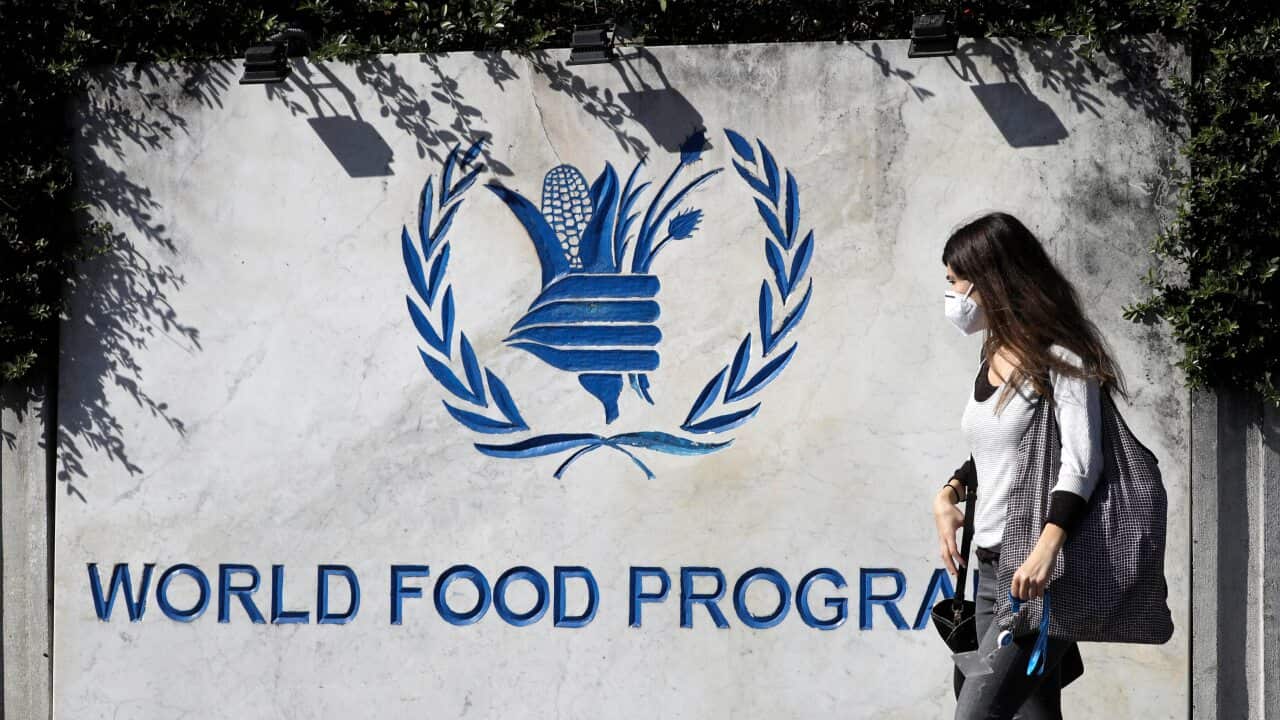A woman walks past a sign at the entrance of the United Nations World Food Program (WFP), in Rome.