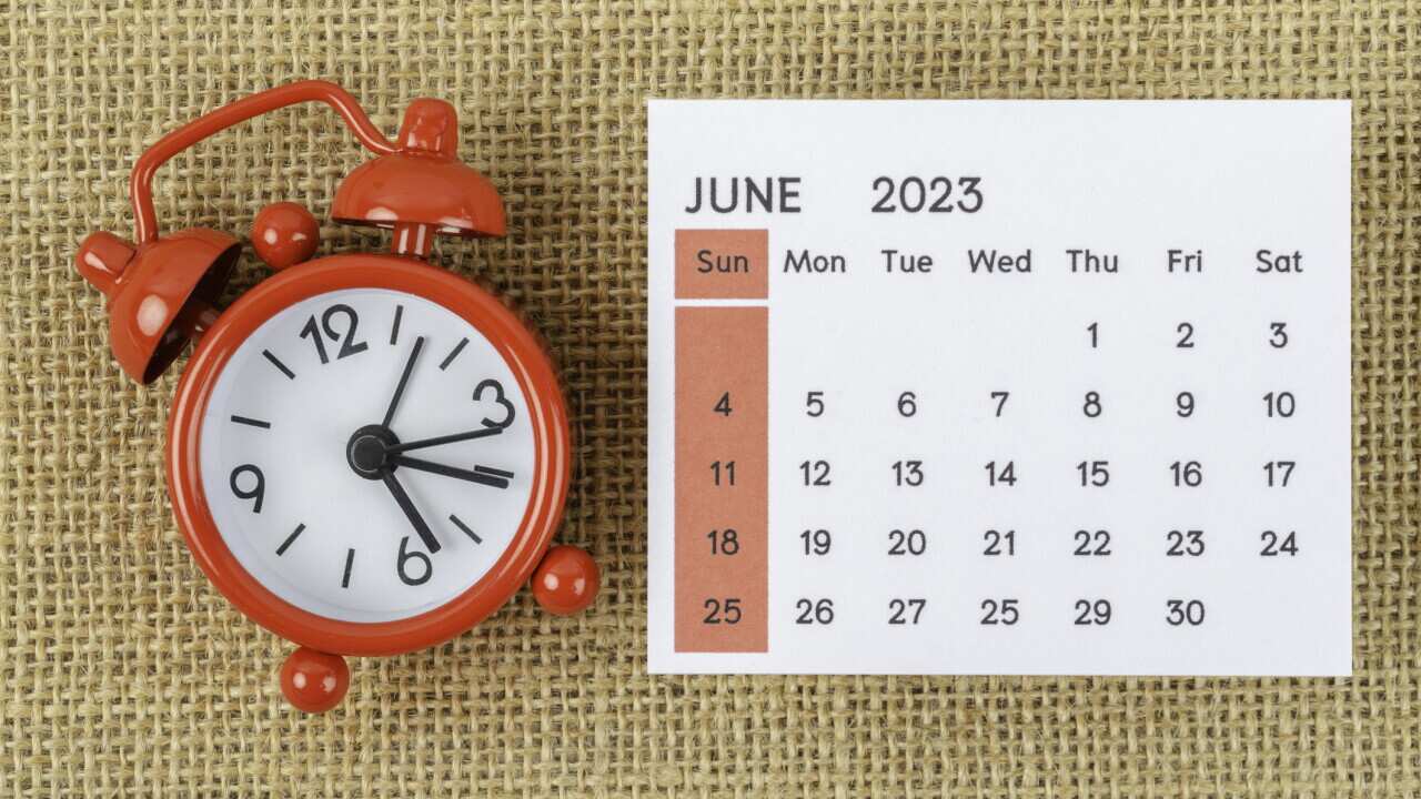 Calendar Desk 2023: June is the month for the organizer to plan and deadline with an alarm clock on a burlap background.