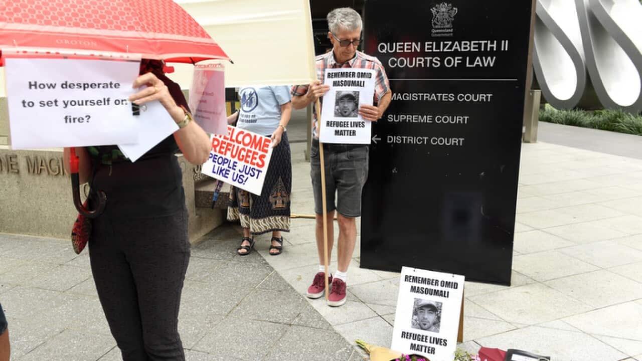 Placards being held outside court in Brisbane , where an inquest was held into the death of Iranian Omid Masoumali