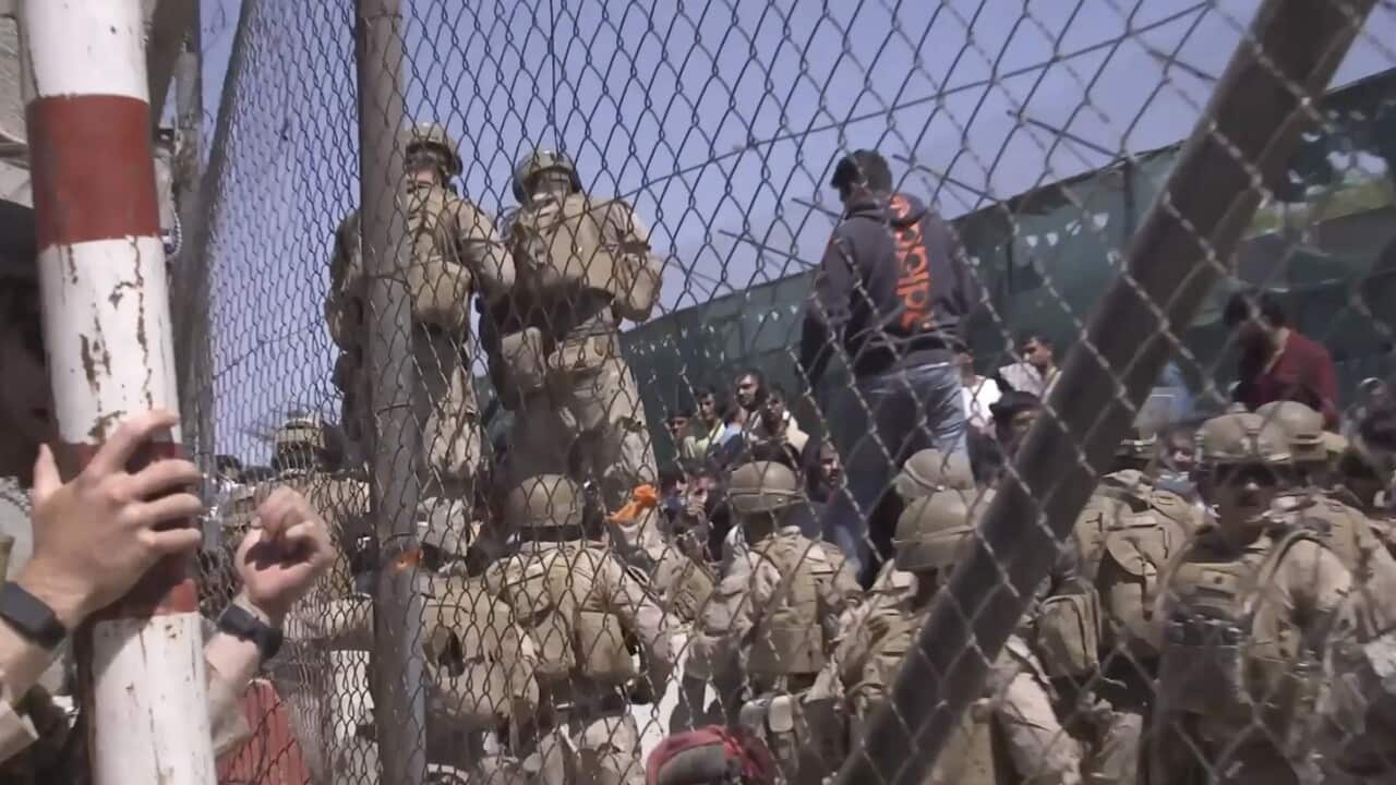 A group of army people surrounding a wired fence