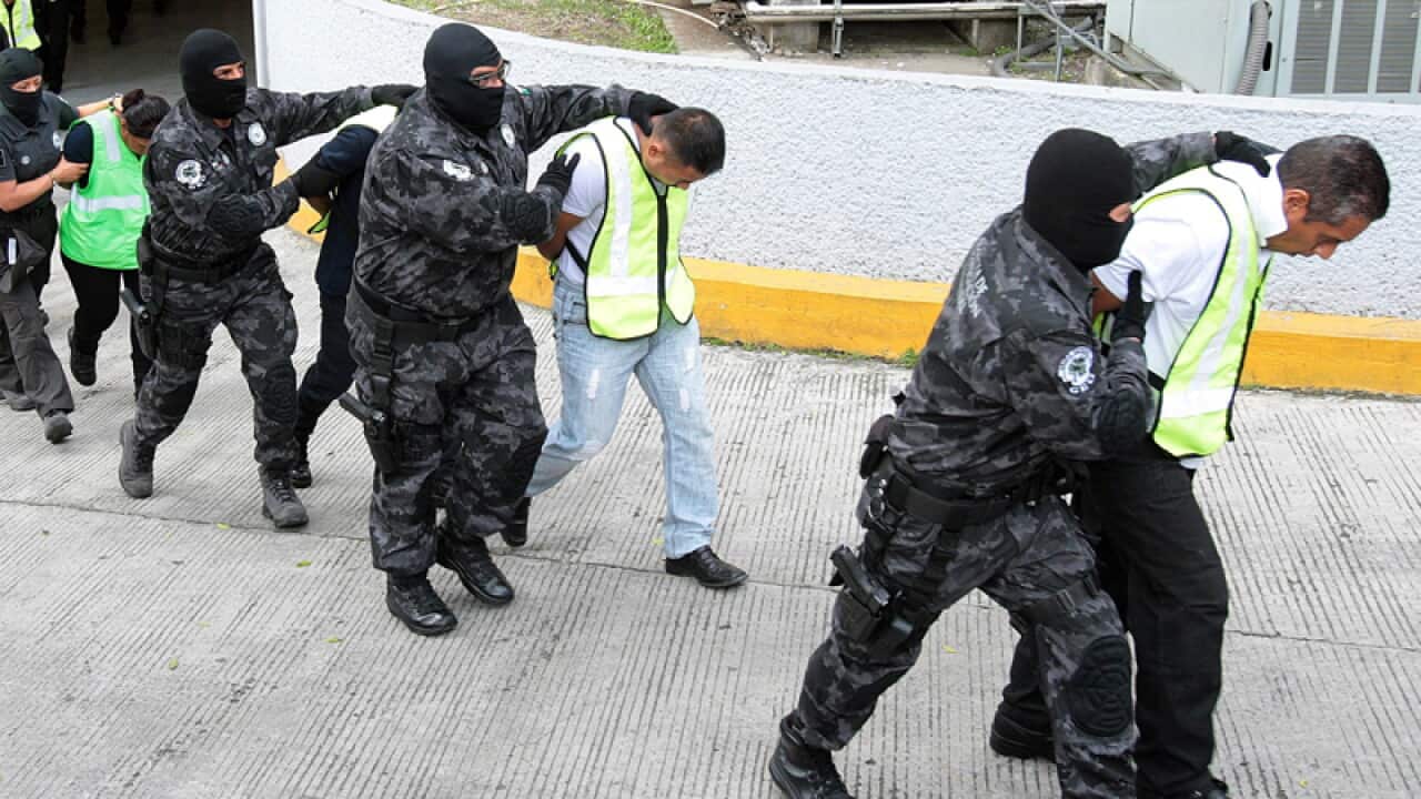 Police escort arrested people in the hunt for the missing students.