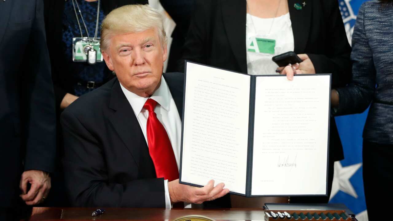 President Donald Trump holds up an executive order for border security and immigration enforcement improvements.