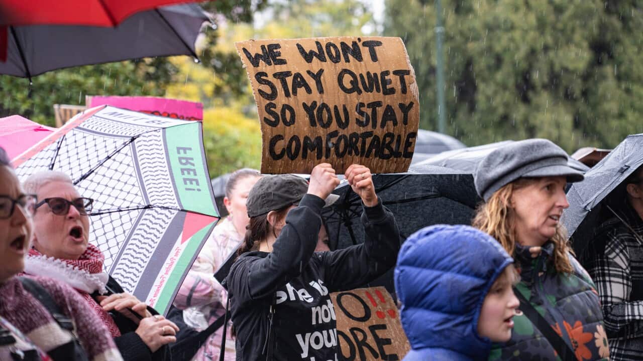 A protester holds a placard that says " We wont stay quiet