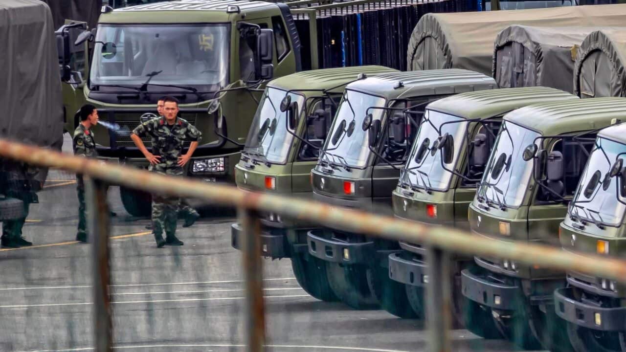 A members of People's Armed Police Force walk by vehicles at the Shenzhen Bay Sports Centre. China has deployed paramilitary personnel, just across the border.