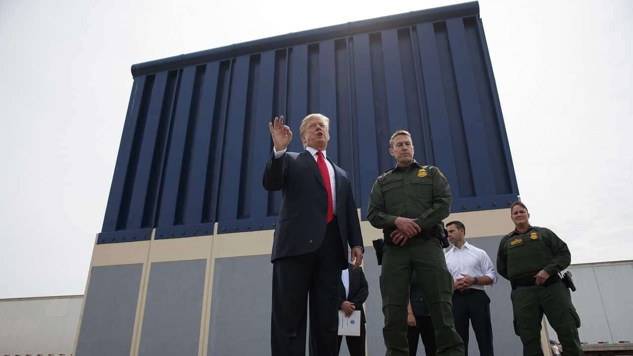 President Donald Trump talks with reporters as he reviews border wall prototypes.