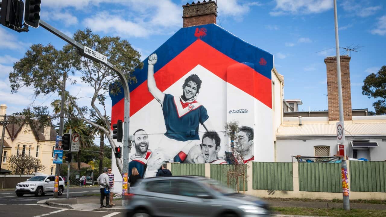 A mural of football legend Artie Beetson atop the shoulders of other historical roosters players.
