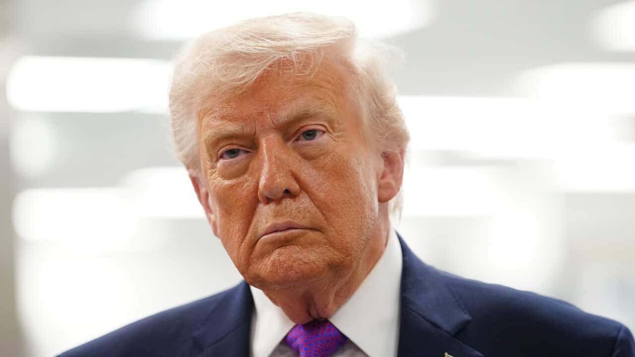 Donald Trump, wearing a blue blazer and American flag pin.