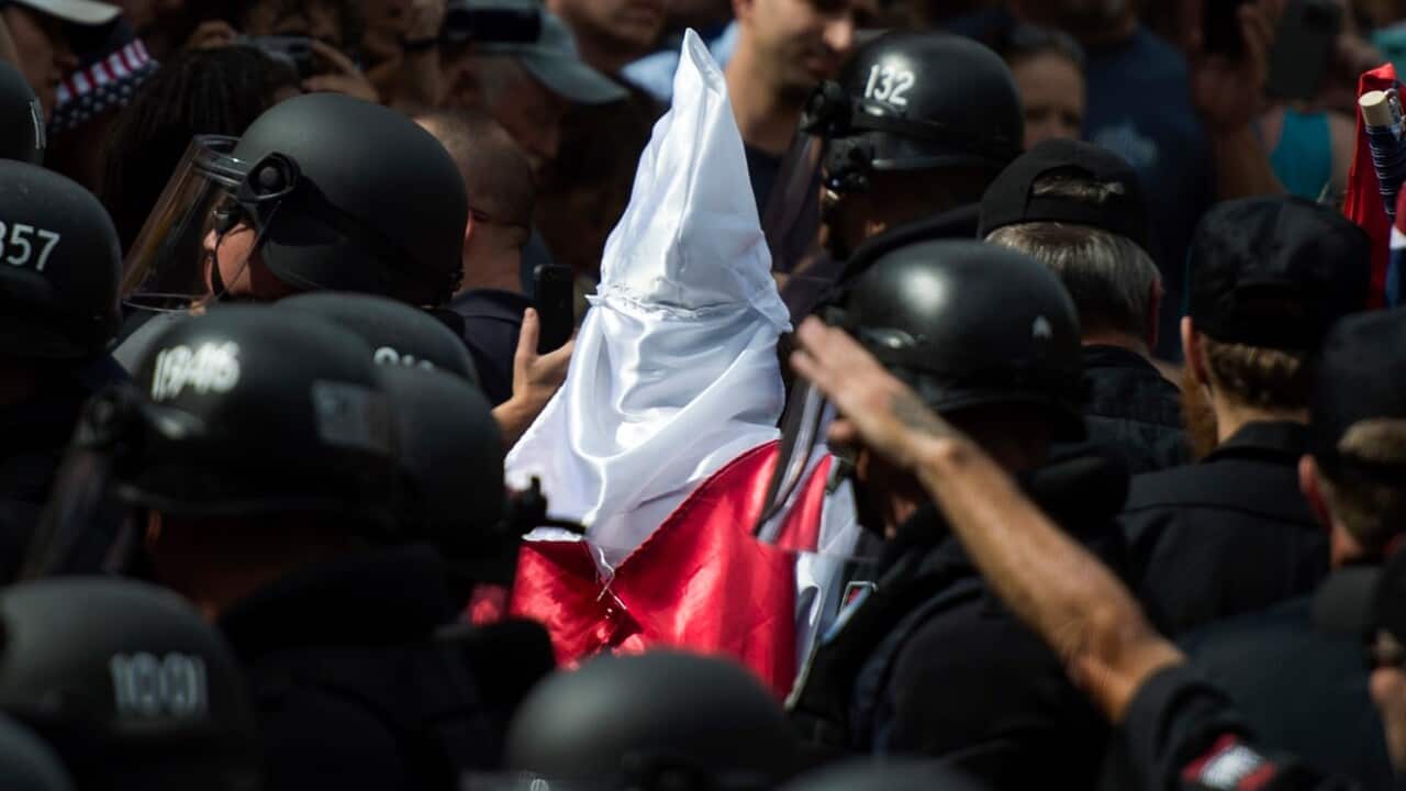 Police escort members of the Ku Klux Klan past protesters following a rally calling for the protection of Southern Confederate monuments in Virginia