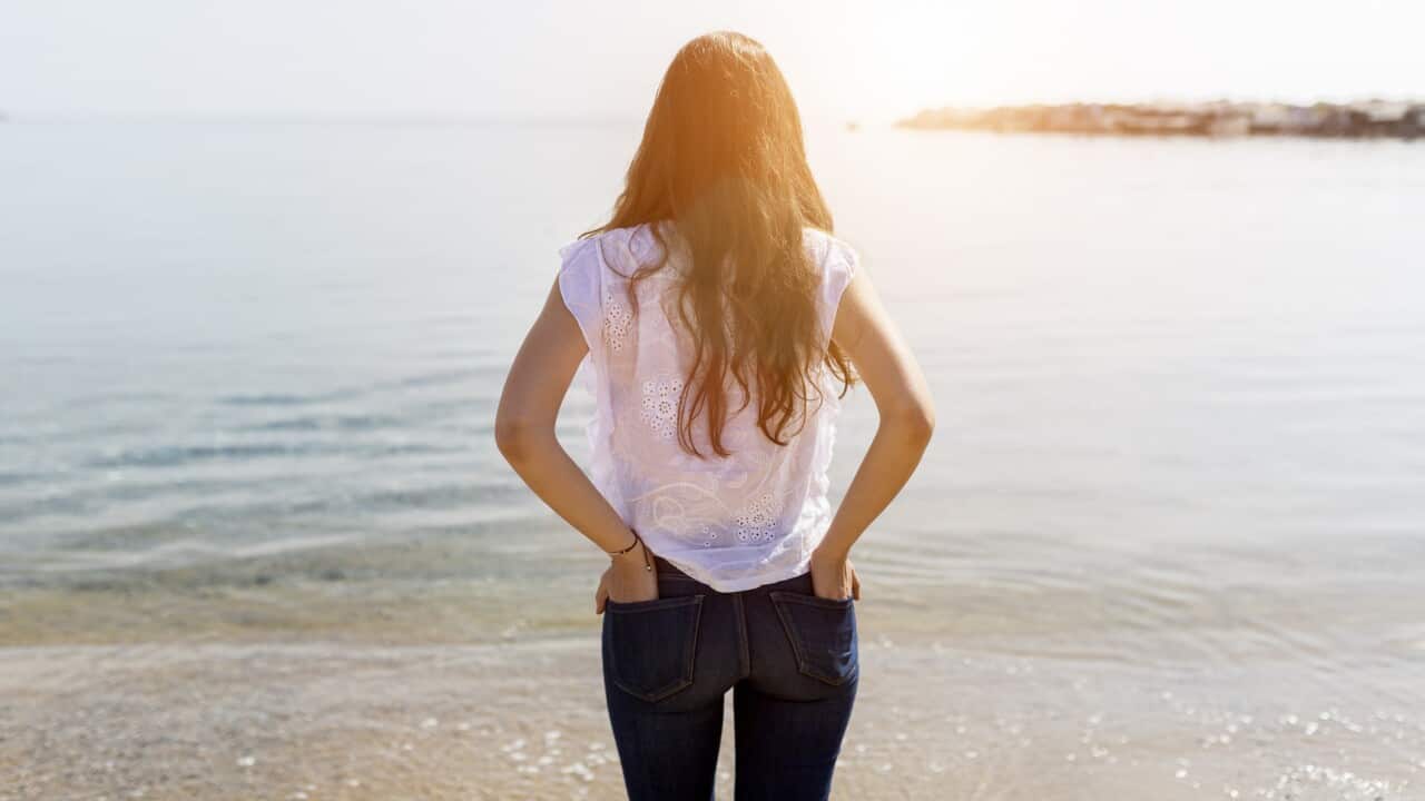 Rear view of young woman standing at the sea