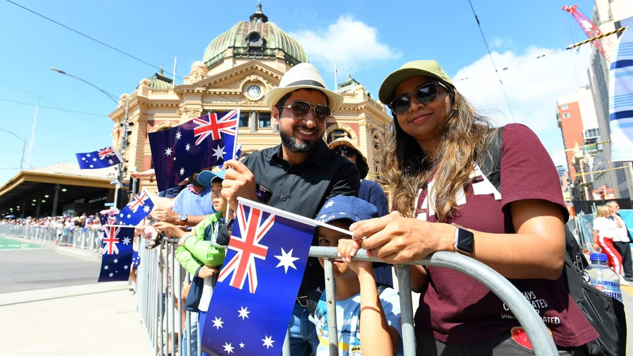 People carry Australian flags in front of Flinders St Station.