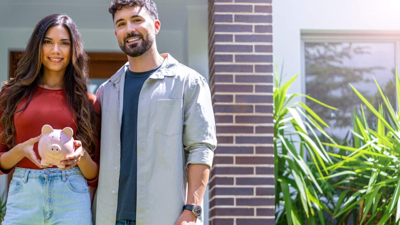 Couple holding a piggy bank in their new home. Home savings concept.