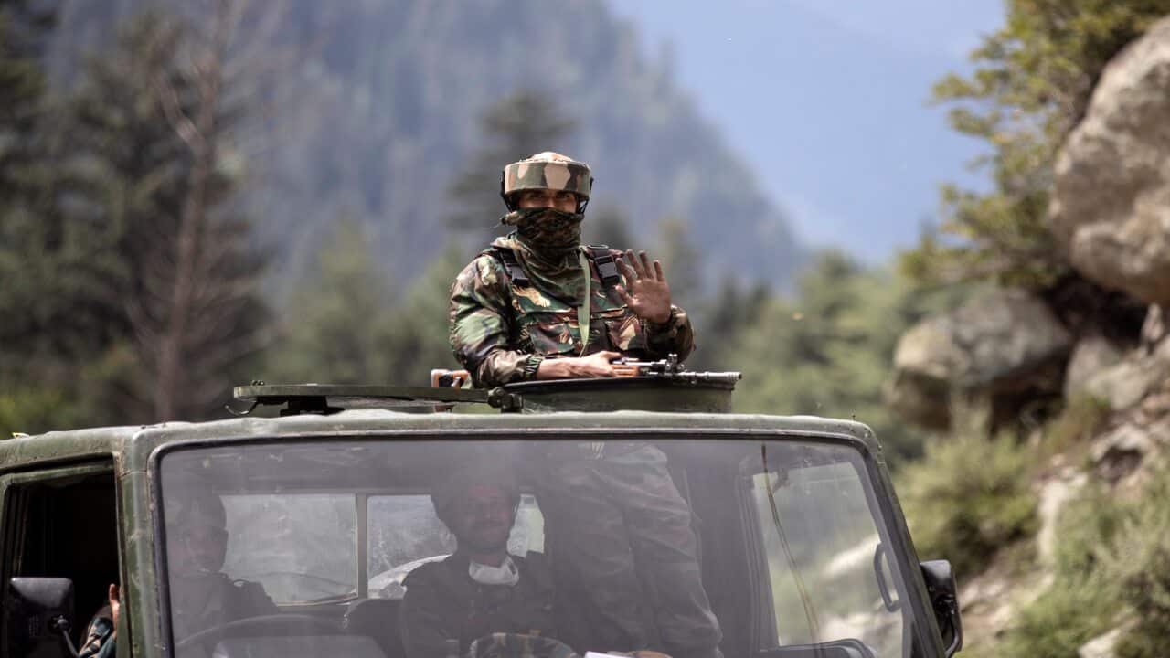 An Indian army soldier waves as their convoy moves.