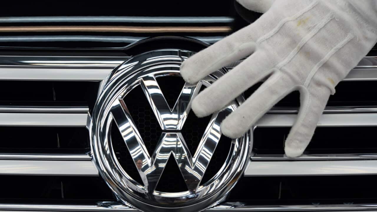A worker touches the logo of Volkswagen AG on a Phaeton in Dresden