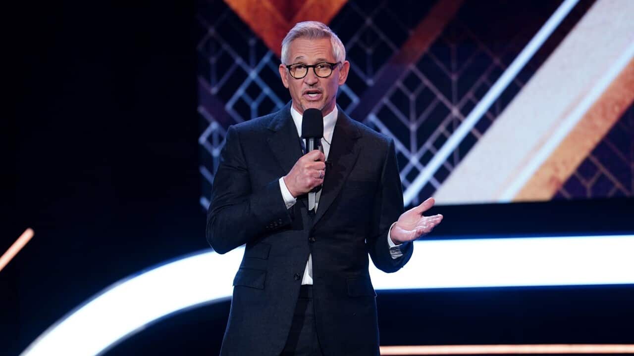 Gary Lineker holds a microphone.