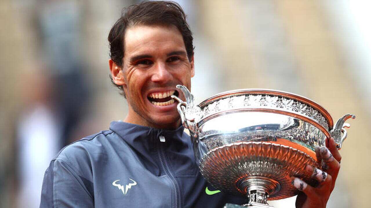 Rafael Nadal bites the winners trophy after victory following the mens singles final against Dominic Thiem of Austria during 2019 French Open at Roland Garros.
