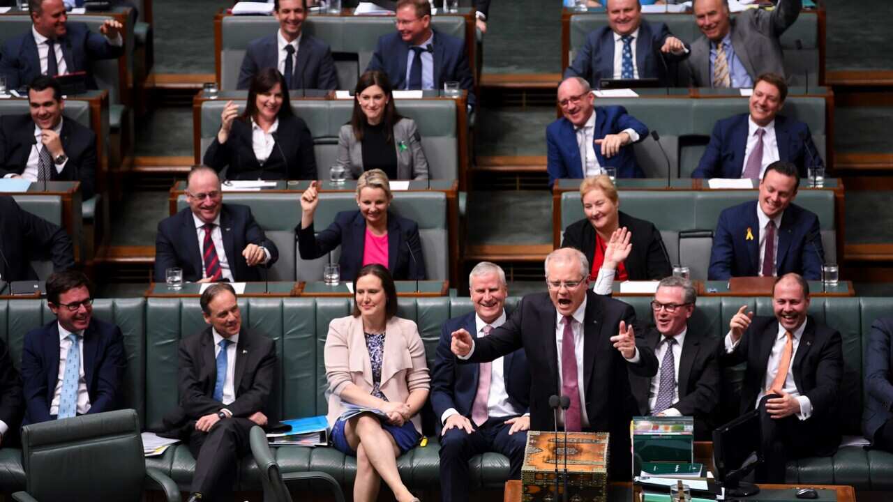 Australian Prime Minister Scott Morrision and his coalition colleagues lift their hands during House of Representatives Question Time.