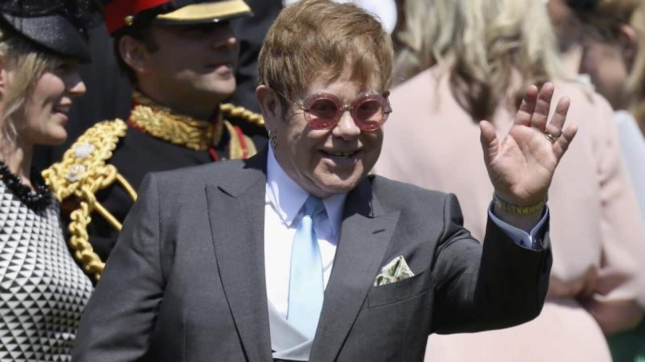 Sir Elton John waves as he arrives for the royal wedding.