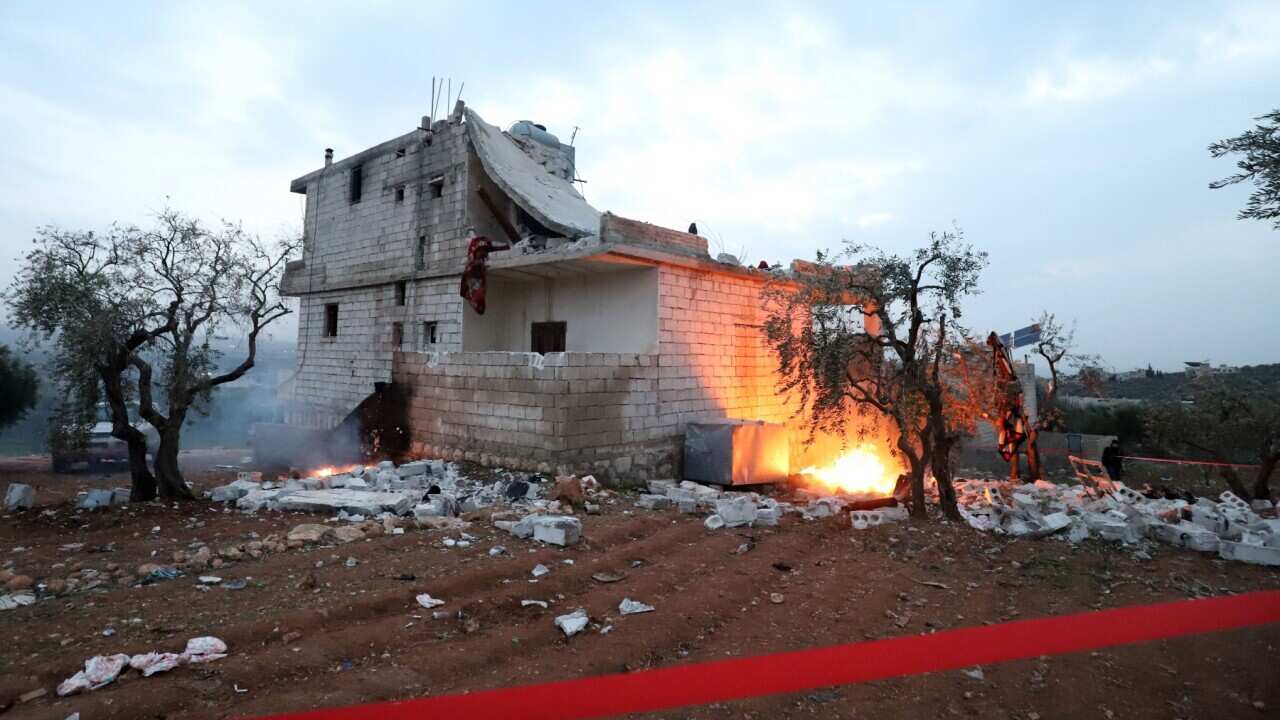 Red tape is extended and objects are set on fire, around the hous in which the leader of Islamic State (IS) group Amir Mohammed Said Abd al-Rahman al-Mawla died, during an overnight raid by US special forces