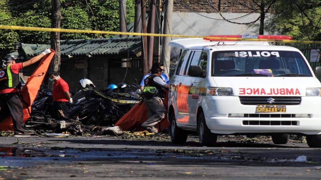 Indonesian police carry body bags at the scene of a bomb blast.