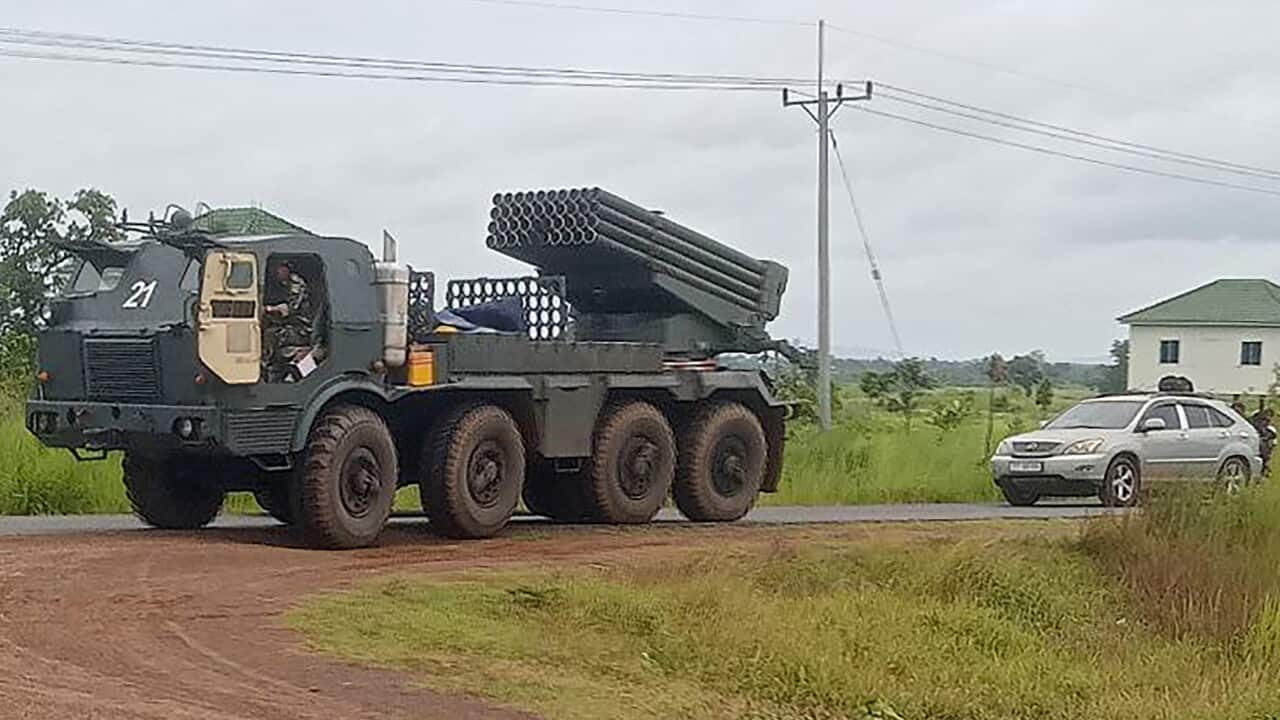 A large vehicle with a rocket launcher driving on a dirt road.