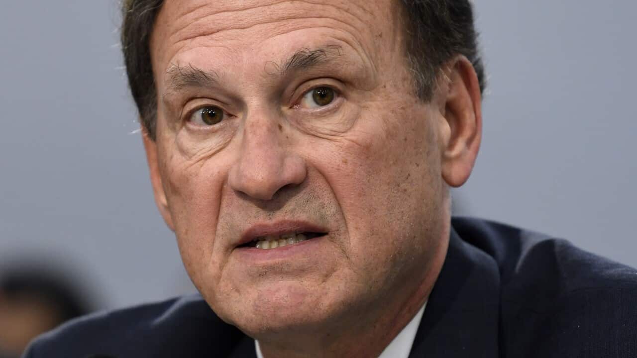 A man speaking into a microphone while seated.