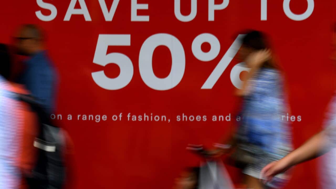 Pedestrians walk past an advertising sign