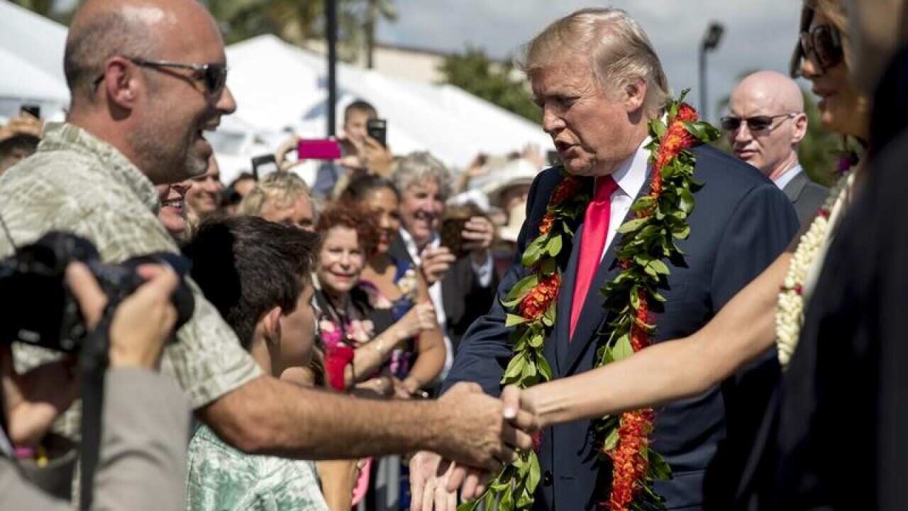 President Donald Trump and first lady Melania Trump wear a lei