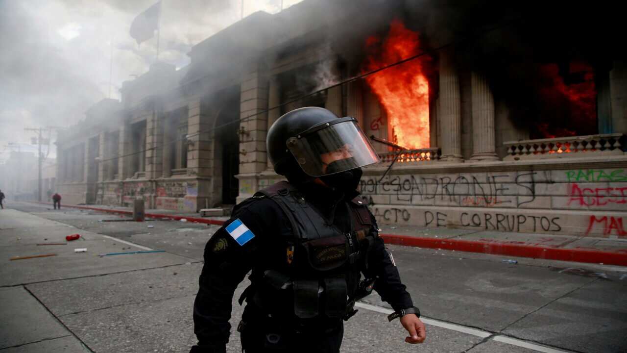 A policeman passes by as Guatemala's Lower House is in flames after hundreds of protesters broke into the building and sat it on fire.