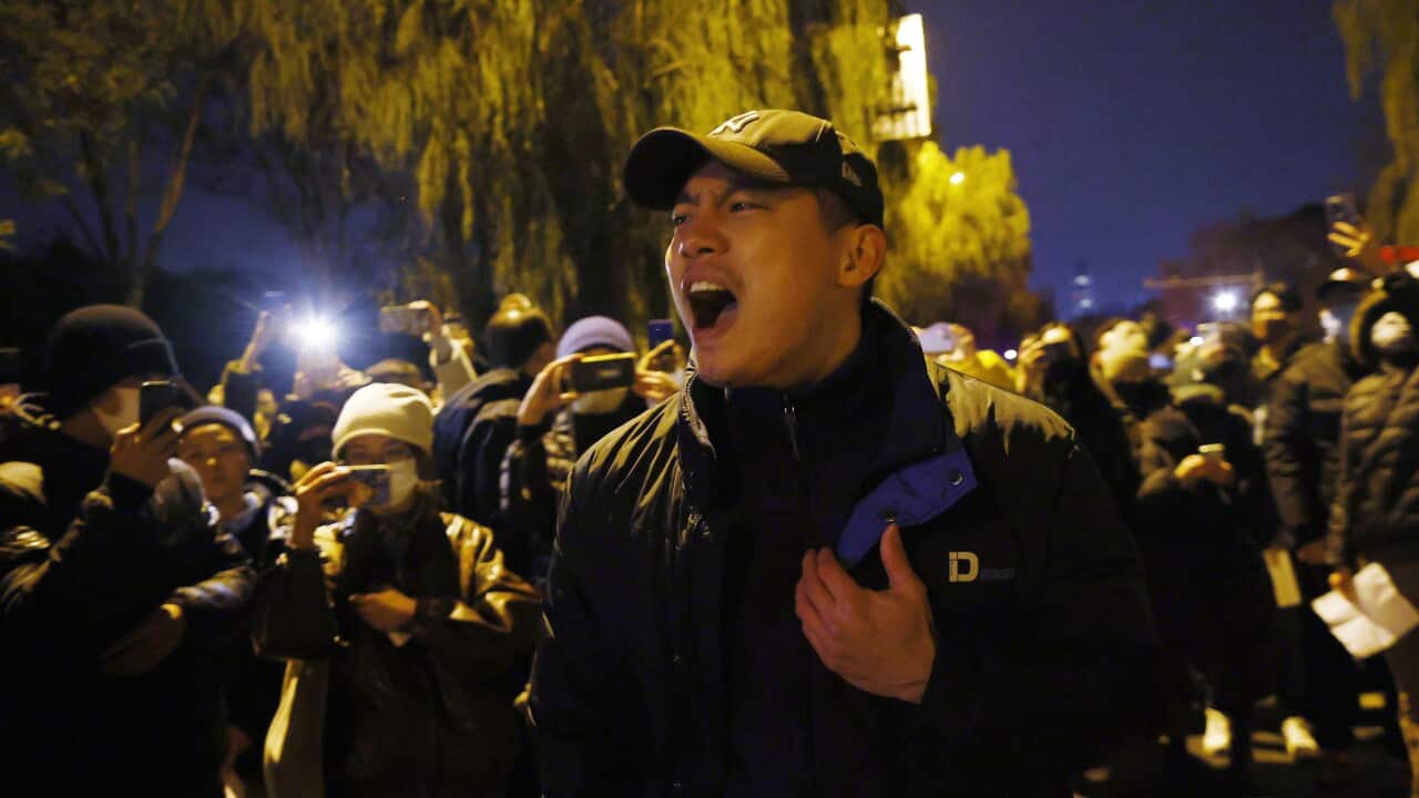 A young man yelling surrounded by a crowd of protesters.