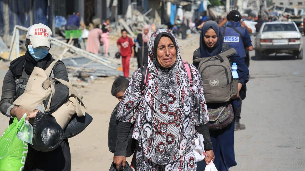 A woman crying as she walks down a dirt road in in northern Gaza