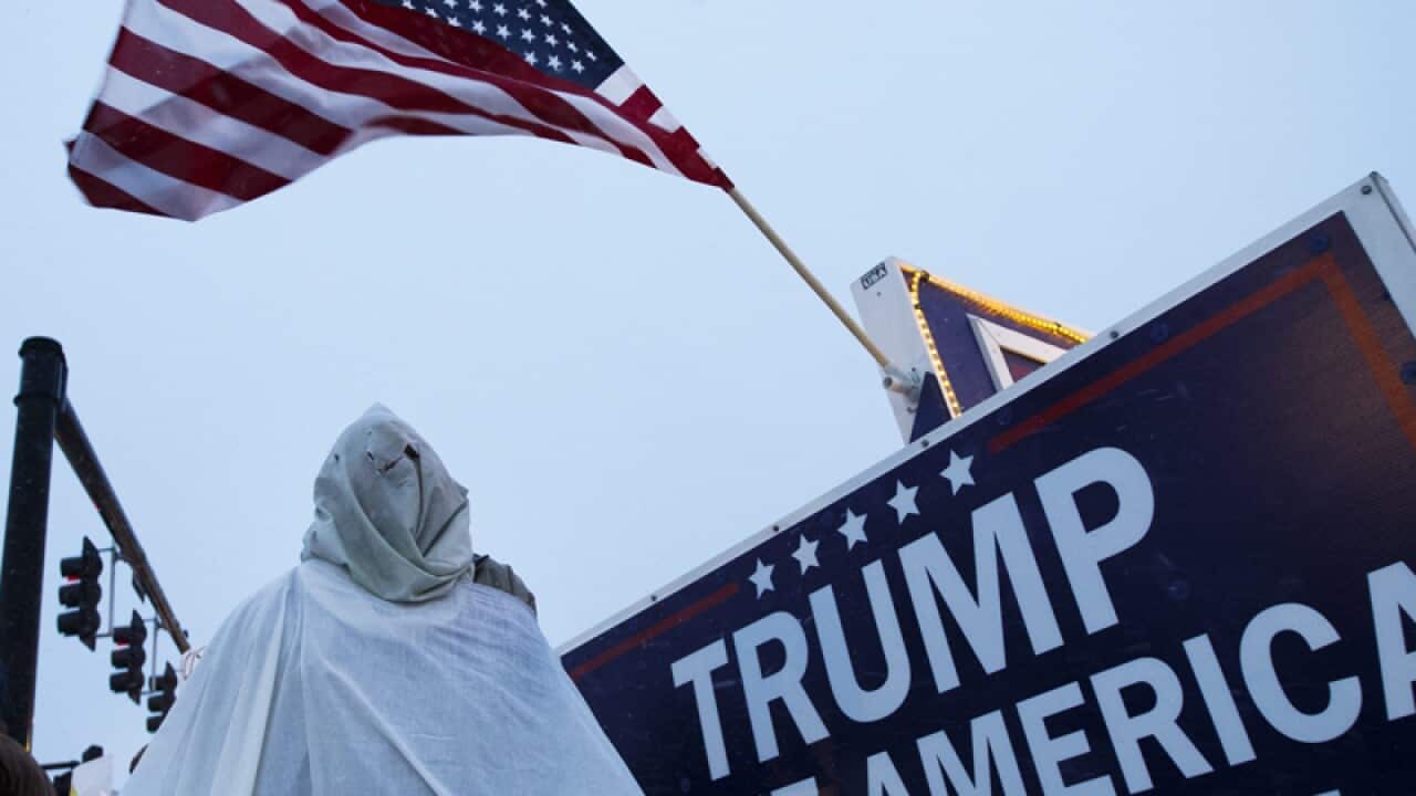A protestor in an outfit resembling a uniform of the Ku Klux Klan