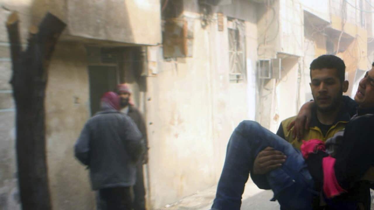 A member of the Syrian Civil Defense group carries a young man wounded during airstrikes and shelling by Syrian government.