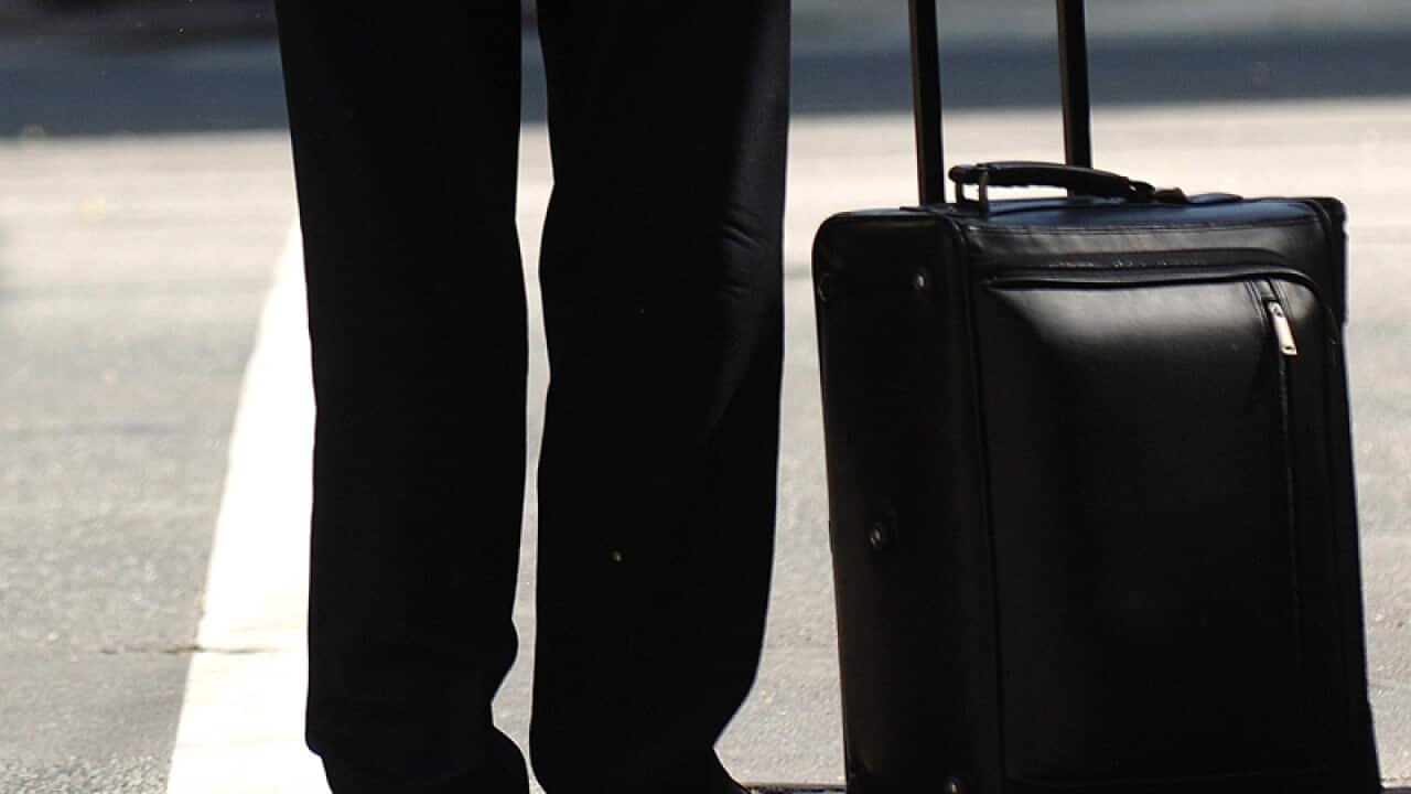 File picture- A man waits with his travel luggage