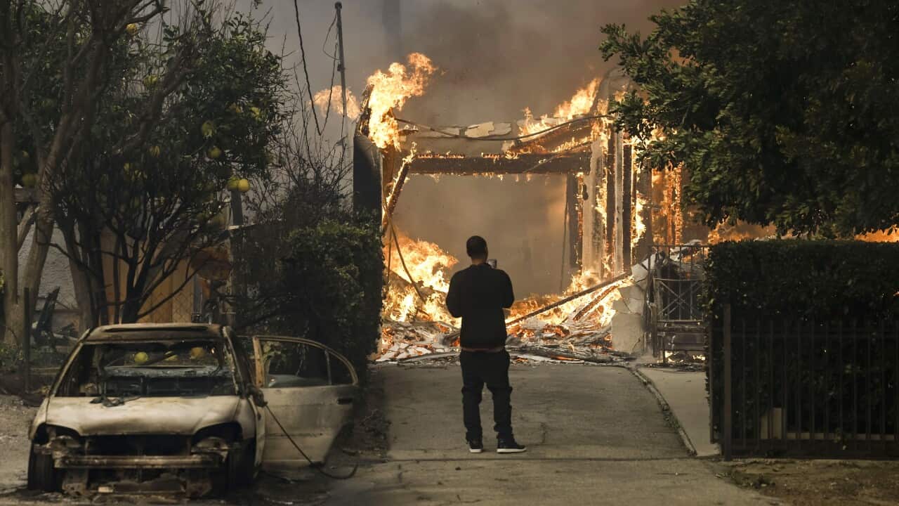 A person watches a house burning