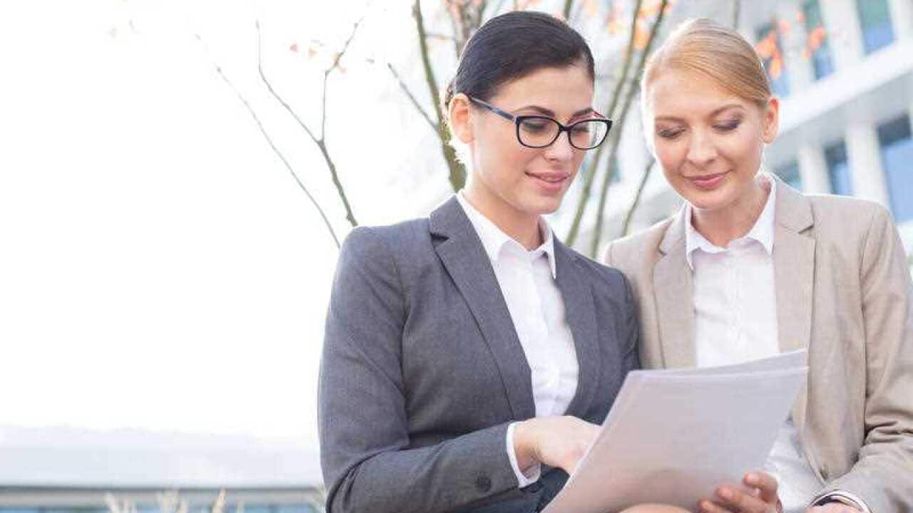 Businesswomen reading documents while sitting outdoors