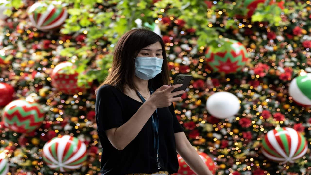 A woman wearing a face mask walking past the Martin Place Christmas Tree in Sydney on 18 December, 2020.