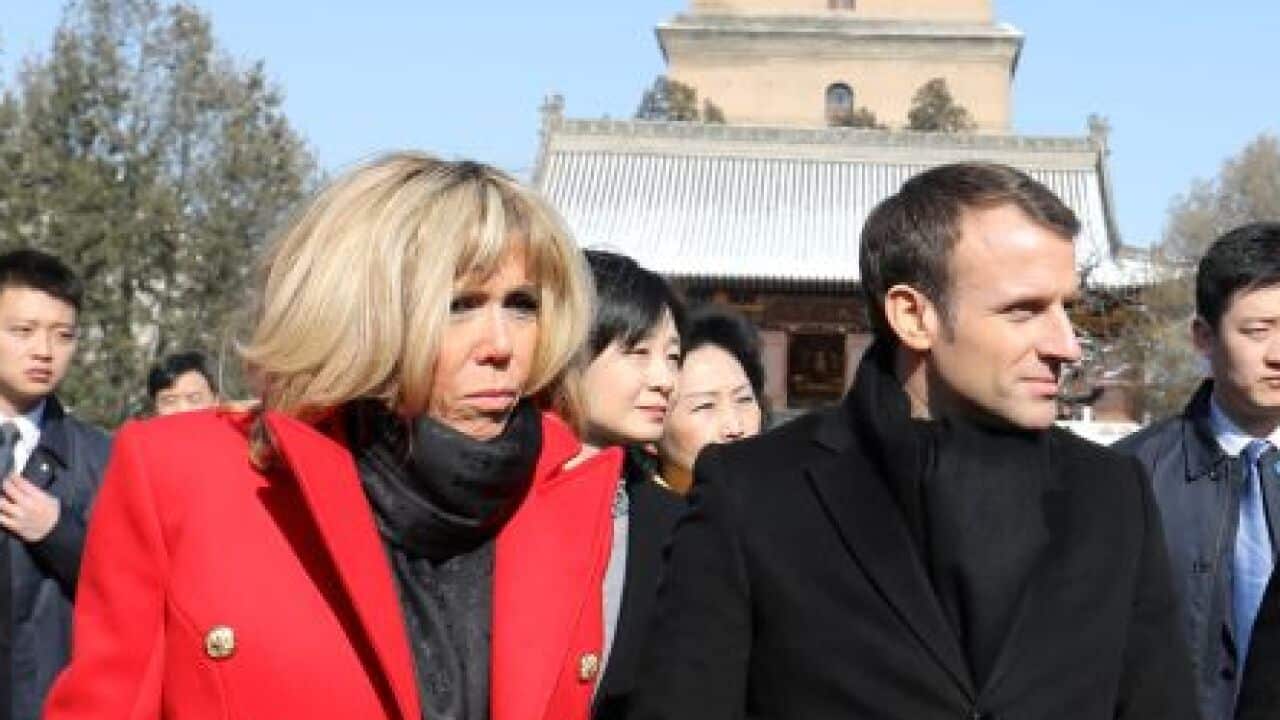 French President Emmanuel Macron and his wife, Brigitte, listen to a priest during a visit at the Big Wild Goose Pagoda in northern China.