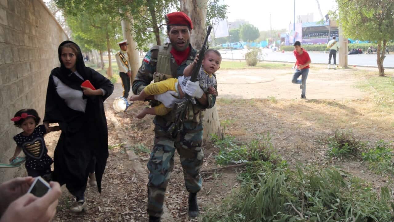 An Iranian soldiers carries a baby as he tries to save a family during a terror attack during a military parade in the city of Ahvaz, southern Iran