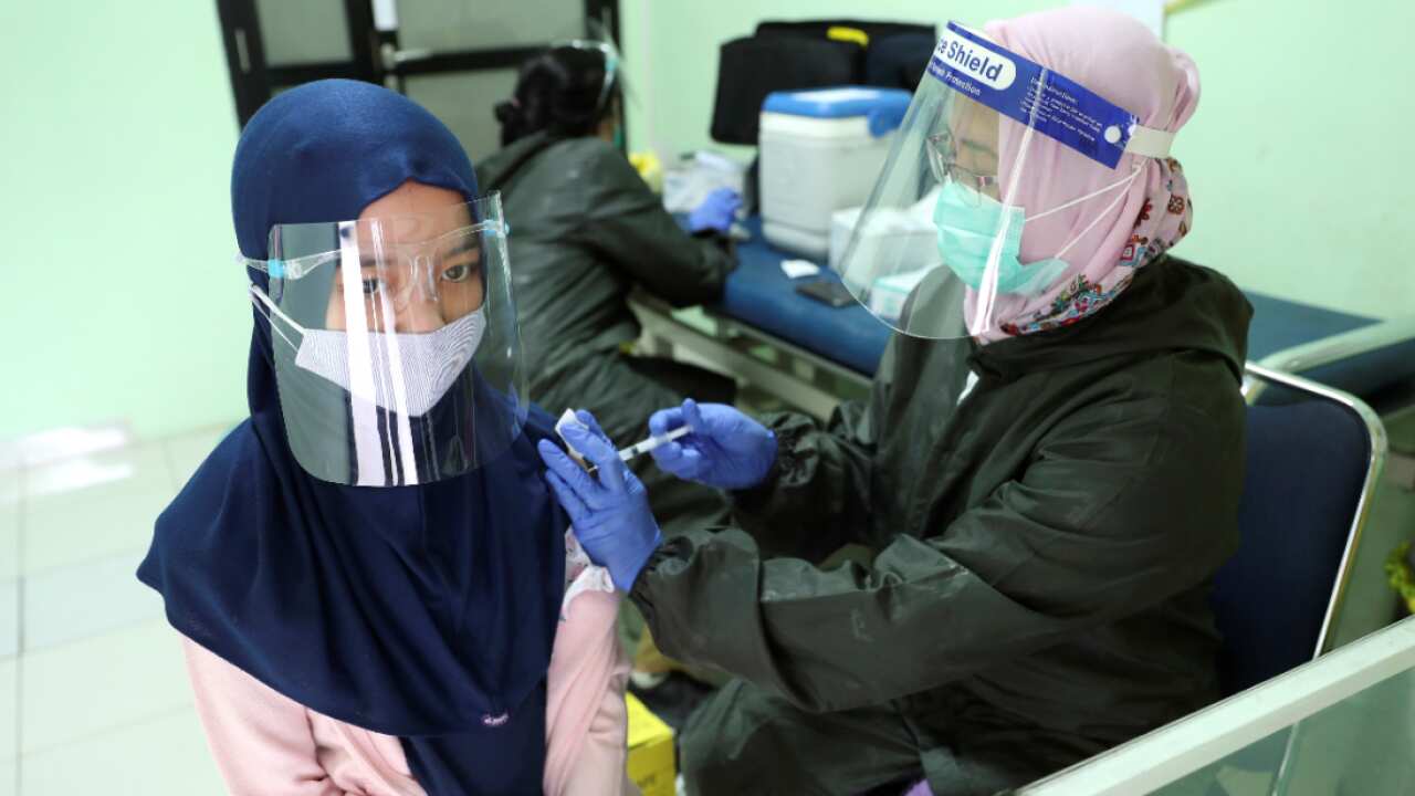 An elementary school student receives a tetanus vaccine shot from a health worker in Jakarta, Indonesia, Tuesday, Oct. 27, 2020.