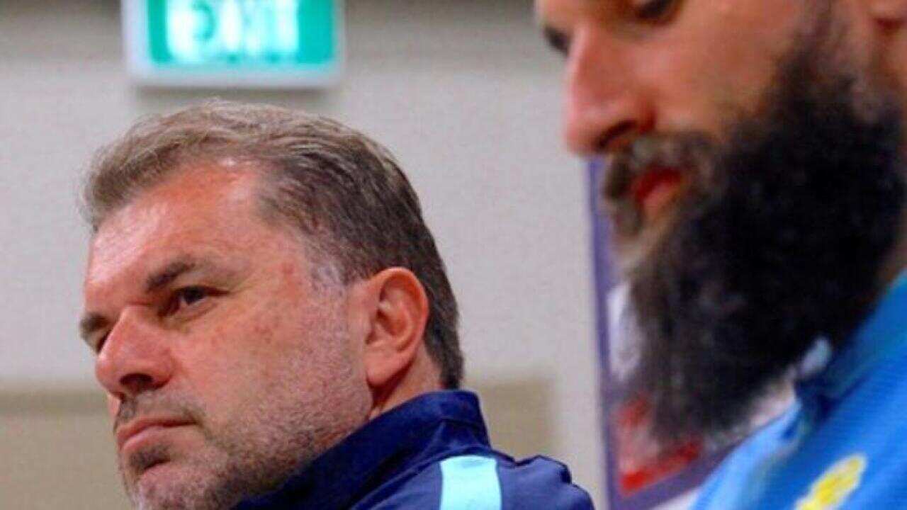 Australian national soccer team coach Ange Postecoglou listens to a question as he sits next to team captain Mile Jedinak during a media conference in Sydney