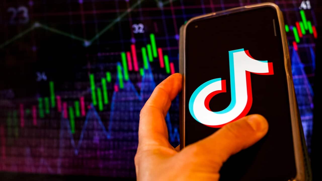 A person holds a phone showing the TikTok logo