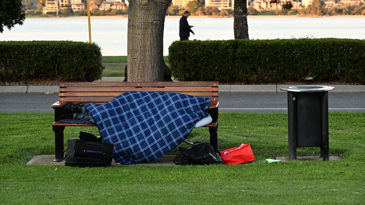 A homeless person sleeping on a park bench
