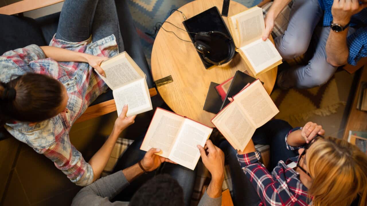Diverse group of friends discussing a book in library.