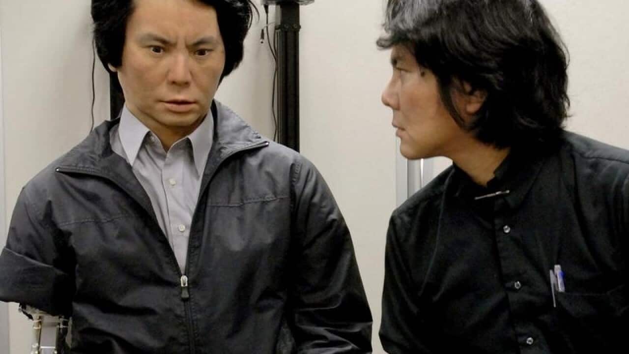 Prof. Hiroshi Ishiguro, right, of Osaka University looking at a robot